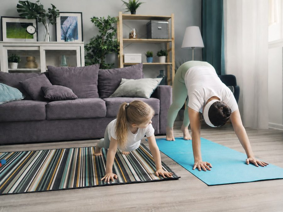 Mamma tränar på yogamatta med sitt barn bredvid
